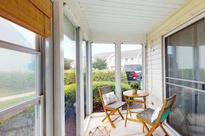 A covered porch with a sliding glass door, two folding chairs, and a small round table. - Townhome with central AC, washer/dryer, & pool access - close to beach (West Ocean City)