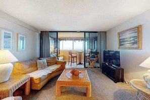 A living room with a sofa, coffee table, TV, and dining area.