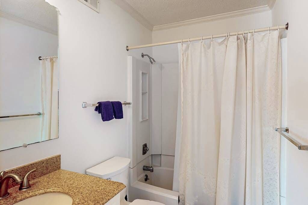 A bathroom with a sink, toilet, shower, and a mirror.