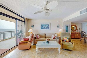 Ein geräumiges Wohnzimmer mit Deckenventilator, einer Sofagarnitur, einem Couchtisch und Meerblick.