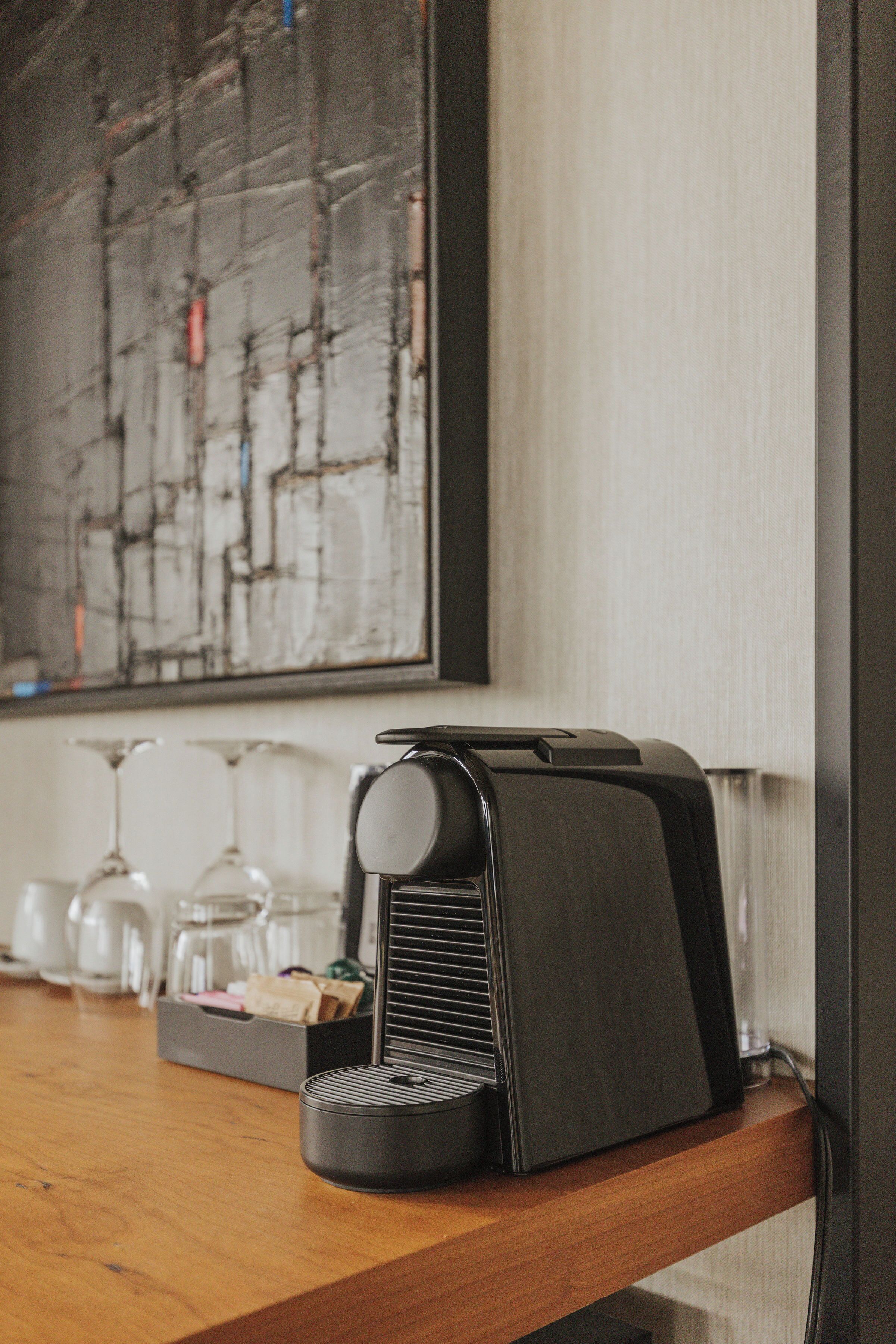 A coffee machine on a wooden counter with a coffee maker and a box of tissues.