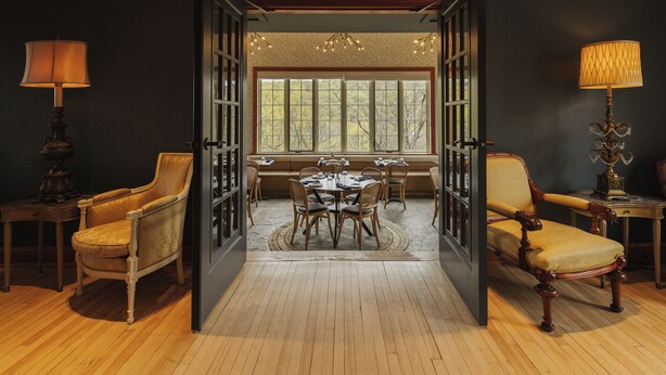 An open room with a dining table, chairs, and a chandelier.