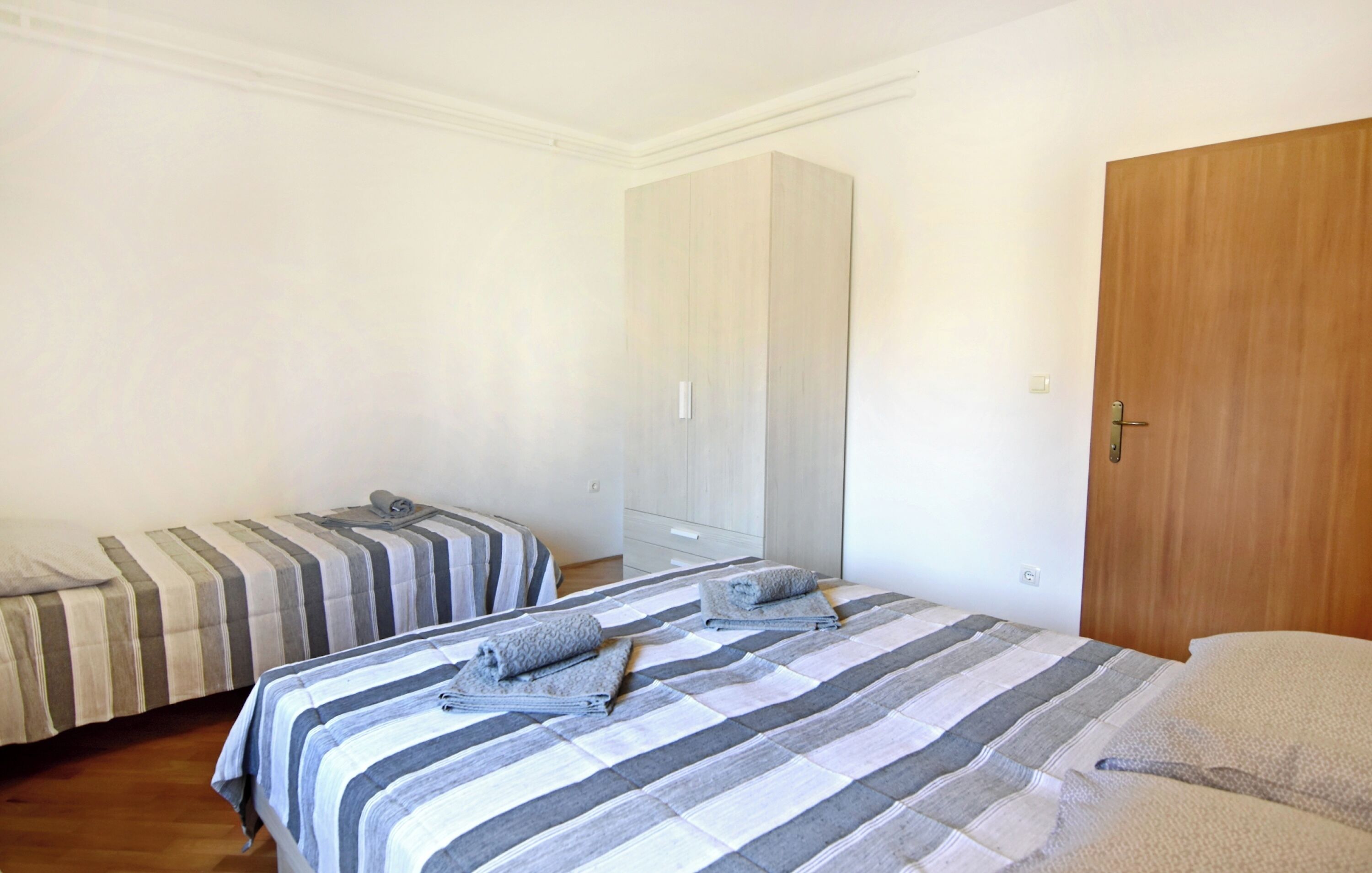 Ein Schlafzimmer mit zwei Betten, einem Kleiderschrank und einer Holztür.