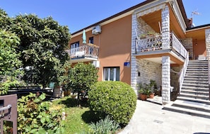 A multi-story building with balconies, a staircase, and potted plants. - Spacious Ground-floor Flat in Umag (Umag)