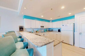 A kitchen with white cabinets, a granite countertop, and a microwave. - Ocean's Edge 303 (Ocean City)