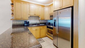 Una cocina con armarios de madera, un refrigerador de acero inoxidable, un microondas y una cafetera.