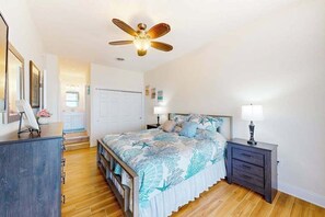 A bedroom with a bed, bedside tables, a ceiling fan, and a view of the hallway. - Spacious Oceanfront - condo on the Boardwalk w/balcony, WiFi, washer/dryer & AC (Ocean City)