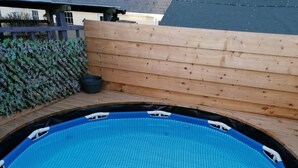 An outdoor swimming pool with a wooden deck surrounding it.