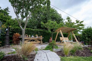 A wooden pergola with a swing, surrounded by a garden with various plants and a stone pathway. - 5 bed Coastal Villa, Fethard-on-sea Hook Penisula (Saltmills)