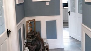 A hallway with blue walls, white trim, a wooden sculpture, and a framed picture.