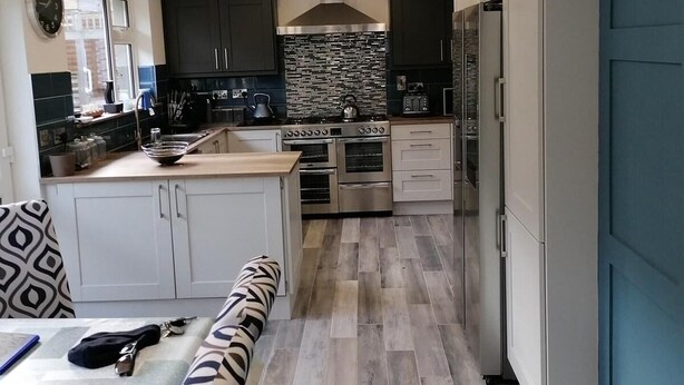 A modern kitchen with white cabinets, a built-in oven, and a blue accent wall.