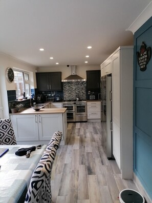 A modern kitchen with a central island, built-in appliances, and a blue accent wall. - 5 bed Coastal Villa, Fethard-on-sea Hook Penisula (Saltmills)