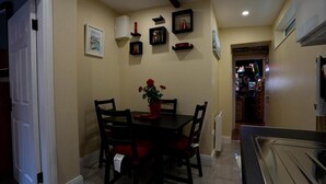 A dining area with a table and chairs, a potted plant, and wall-mounted shelves with various items.