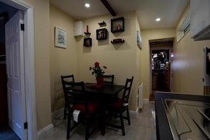 A dining area with a table and chairs, a potted plant, and wall-mounted shelves with various items.
