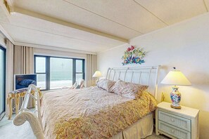 A hotel room with a bed, bedside lamps, a TV, and a window with a view. - Waterfront condo w/ocean views, beach access, private balcony, W/D, & Central AC (Ocean City)