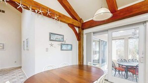 A dining area with a wooden table and chairs, a ceiling fan, and a view through a glass door to an outdoor patio. - 13904 Lighthouse Ave (Ocean City)