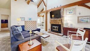 A living room with a fireplace, wooden beams, a sofa, and a television. - 13904 Lighthouse Ave (Ocean City)