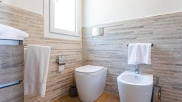 Ein modernes Badezimmer mit Toilette, Waschbecken und Handtuchhalter vor einer strukturierten Wand.