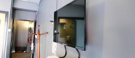 Un pasillo con una televisión de pantalla plana montada, un teléfono y un perchero.