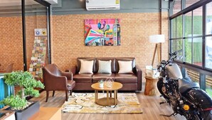 A modern interior with a brick wall, a sofa, a coffee table, a motorcycle, and a large window.