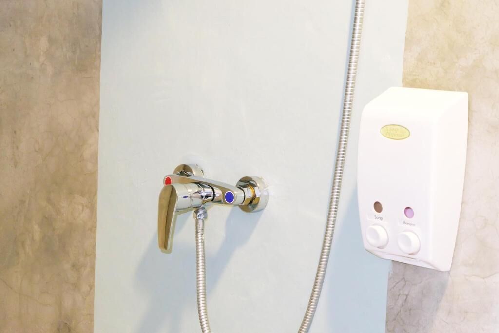 A shower with a handheld showerhead and a control panel with buttons for water temperature and flow.