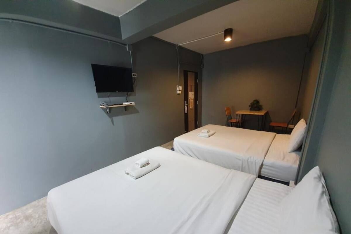 A hotel room with two beds, a flat-screen TV mounted on the wall, and a small table with chairs.