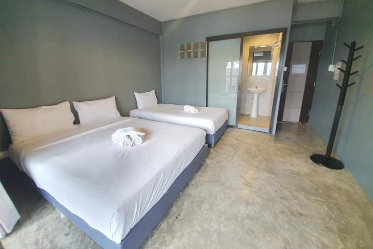 A hotel room with two beds, a bathroom with a sink, and a sliding door leading to another room.