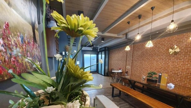 A modern interior with a brick wall, hanging light fixtures, a bench, and a large floral arrangement.