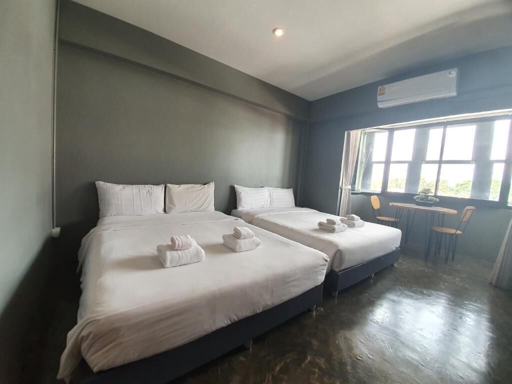Habitación de hotel con dos camas, una mesita y un ventanal.