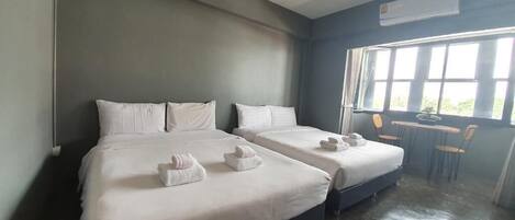 Habitación de hotel con dos camas, una mesita y un ventanal.