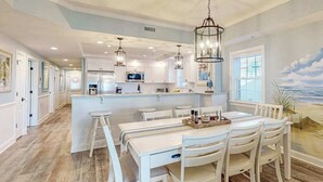 A spacious kitchen with white cabinetry, a central island, and pendant lighting. - Sunny - Ocean Block Condo, steps to the beach with pool, balcony & fitness room (Ocean City)