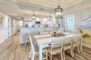 A spacious kitchen with white cabinetry, a central island, and pendant lighting. - Sunny - Ocean Block Condo, steps to the beach with pool, balcony & fitness room (Ocean City)
