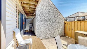 Een overdekt terras met houten plafond, stenen muur en tuinmeubilair.
