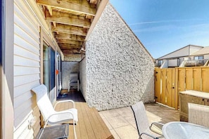 A covered patio area with a wooden ceiling, a stone wall, and outdoor furniture. - Club Ocean Villa II 184 (Ocean City)