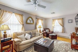 A living room with a sofa, armchair, ottoman, and a ceiling fan. - 416 - 141st St (Ocean City)