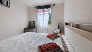 Un dormitorio con cama, mesita de noche, cómoda y ventana con cortina.