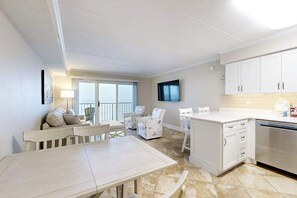 A spacious living area with a dining table, chairs, a sofa, and a TV. - Marigot Beach 1205 (Ocean City)