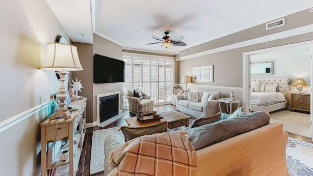A spacious living room with a fireplace, a ceiling fan, and a large window. - 2nd-floor condo near the beach with pool, balcony, gym, fireplace, & jetted tub (Ocean City)