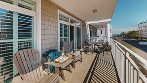 A balcony with outdoor furniture, a table with a tray, and a view of the street. - 2nd-floor condo near the beach with pool, balcony, gym, fireplace, & jetted tub (Ocean City)