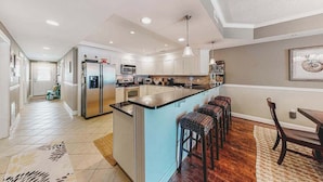 A spacious kitchen with a central island, stainless steel appliances, and a dining area with a table and chairs. - 2nd-floor condo near the beach with pool, balcony, gym, fireplace, & jetted tub (Ocean City)
