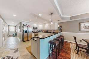 A spacious kitchen with a central island, stainless steel appliances, and a dining area with a table and chairs. - 2nd-floor condo near the beach with pool, balcony, gym, fireplace, & jetted tub (Ocean City)