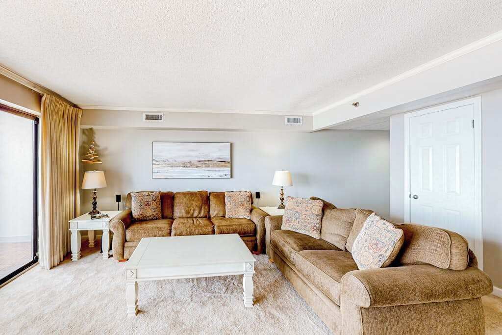 A living room with a beige sofa set, a white coffee table, and two lamps.