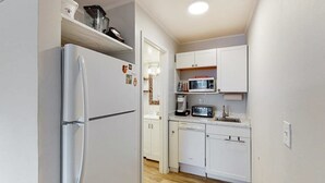 A compact kitchen with white cabinets, a built-in microwave, and a refrigerator. - Ocean Waye 226 (Ocean City)