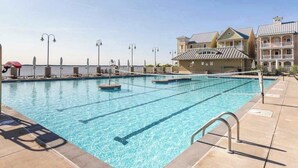 Une piscine avec plusieurs couloirs de nage, un poste de surveillance pour les sauveteurs et un bâtiment doté de balcons.