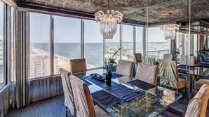 Une chambre située dans un immeuble de grande hauteur, avec une table en verre, des fauteuils en cuir et une vue sur l’océan.