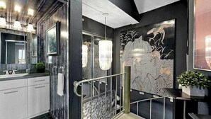 Une salle de bain moderne avec un grand miroir, un lustre et un élément décoratif mural.