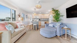 A living room with a sofa, a coffee table, and a TV mounted on the wall. - Beachcrest 14 (Ocean City)