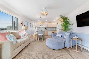 A living room with a sofa, a coffee table, and a TV mounted on the wall. - Beachcrest 14 (Ocean City)