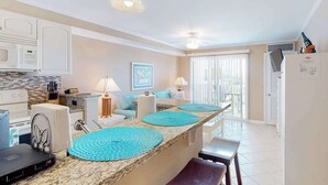 A kitchen with a central island, a dining area with a bench, a ceiling fan, and a refrigerator. - Makai 403 (Ocean City)
