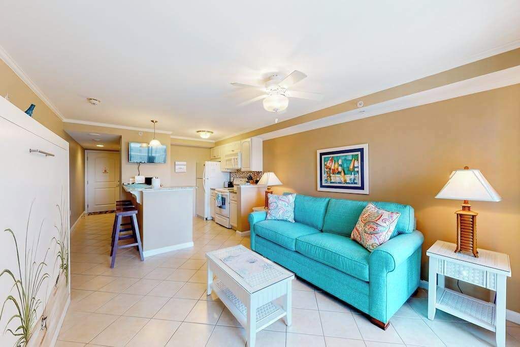 A living room with a sofa, a coffee table, a TV, and a ceiling fan.